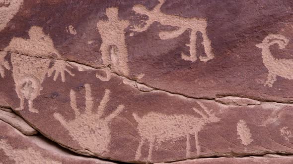 Panning over petroglyph carving of people and hands