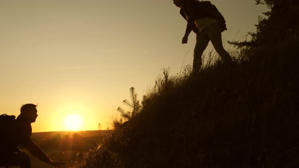 Traveler Woman Extends a Hand To a Man To a Traveler Climbing To the Top of a Hill. Tourists Climb