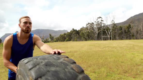 Fit man pushing heavy tyre during obstacle course