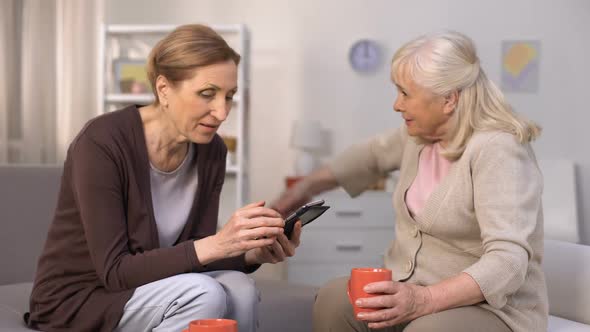 Senior Woman Using Smartphone Communicating With Her Mature Neighbour, Friends