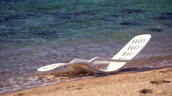 White plastic sun lounger in sea water on a tropical beach in Egypt