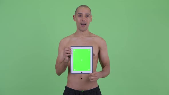 Happy Bald Multi Ethnic Shirtless Man Showing Digital Tablet and Looking Surprised