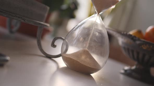 Hourglass sand falling in slow motion paning up