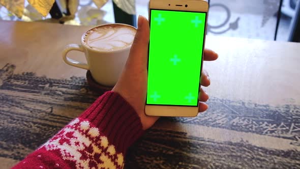 Female Holding Green Screen Phone with a Cup of Coffee