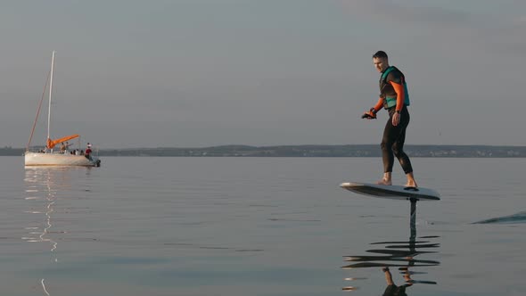 Man Riding on a Hydrofoil Surfboard on Large Lake at Golden Sunset