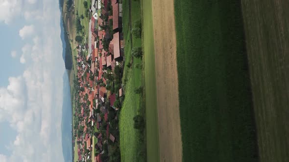 Vertical flyover above houses and farmland around Delnita, Romania