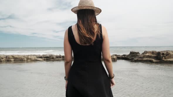 Girl In A Hat And Black Dress Looking At A Puddle