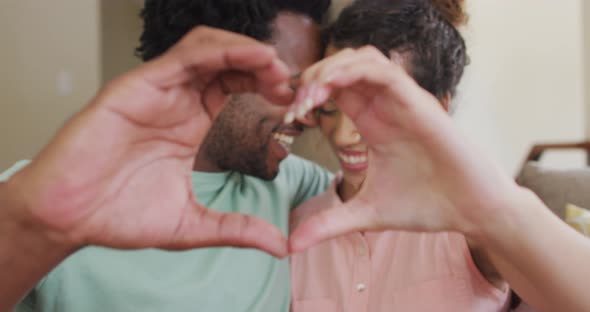 Happy biracial couple gesturing heart sign with hands