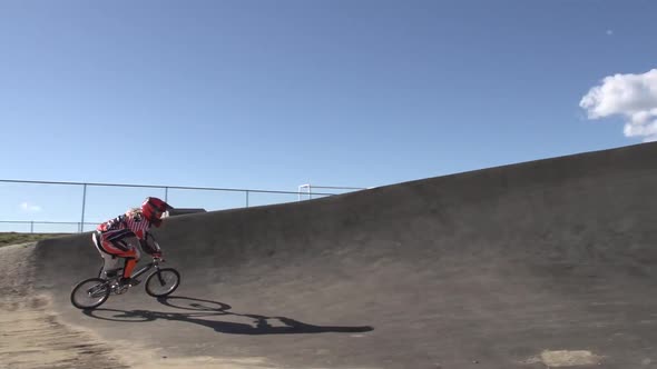 A young woman bmx rider riding on dirt track.