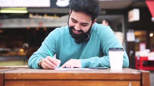 Man with headphones reading and writing a document