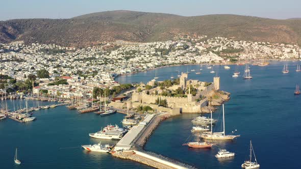 aerial drone circling Bodrum Castle surrounded by boats anchored in the blue Aegean Sea on a sunny s