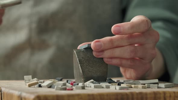 Male Hands Break the Mosaic Tiles in Half Using a Special Hammer