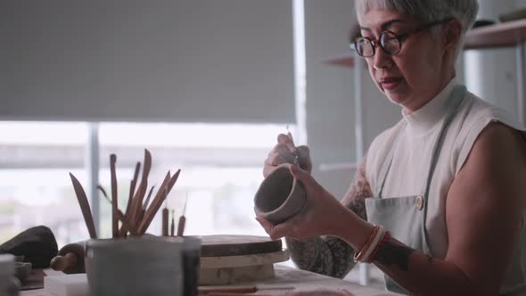 Asian elderly woman enjoying pottery work at home.