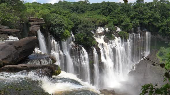 Kalandula Falls spraying water over bushes and tart-like rocks