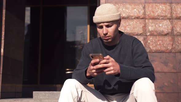 Thoughtful Caucasian Man Reading Serious News on Phone Outdoor. Serious Man Typing on Phone at