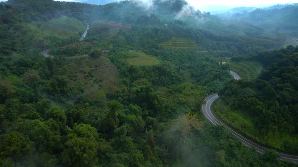 Aerial view over a winding road in the mountains of a tropical forest, Thailand.