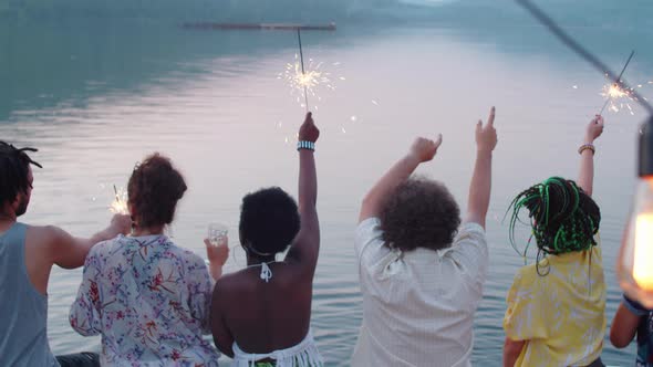 Friends Dancing with Sparklers on Lake Party