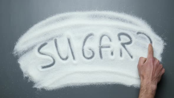 Male hand writes text sugar? on surface of sugar. No sugar. Prevent diabetes mellitus disease.