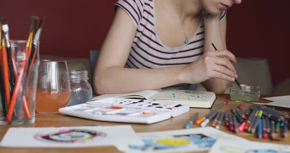 Portrait of woman painting with watercolors at home