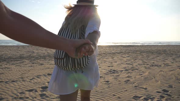 Follow Me Shot of Young Woman in Shirt with Backpack Pull Her Boyfriend to Sea Shore