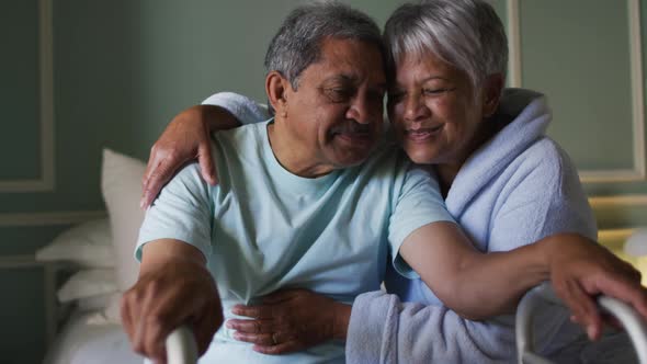 Smiling senior mixed race couple embracing, man holding walking frame