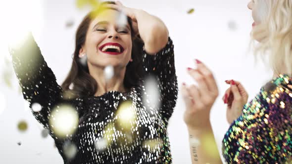 Two women dancing under shower of confetti in studio shot