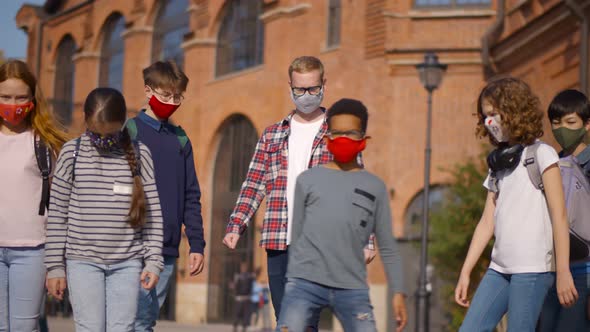 Diverse School Children and Male Teacher Standing Outdoors with Face Mask and Looking at Camera