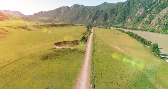 Aerial Rural Mountain Road and Meadow at Sunny Summer Morning. Asphalt Highway and River.