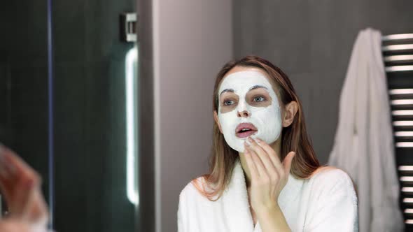 Beautiful Woman in Bathrobe Putting White Mask for Moisturizing Using Fingers Slowmo