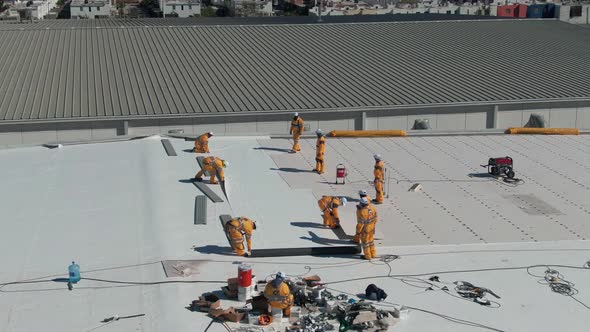 Workers Waterproofing an Industrial Rooftop