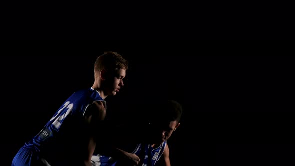 Athletes are Engaged in Basketball in a Dark Studio on a Black Background