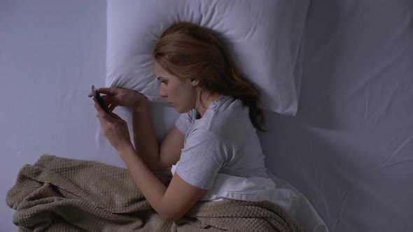 Sad Woman Crying Reading Old Messages on Smartphone Lying in Bed, Memories