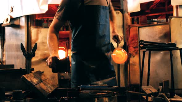 Mid section of glassblower shaping a molten glass