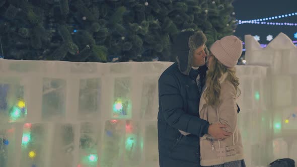 Happy Couple Kisses at Beautiful Christmas Tree on Square