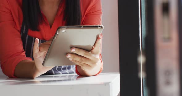 Video of midsection of biracial waitress using tablet at coffee shop