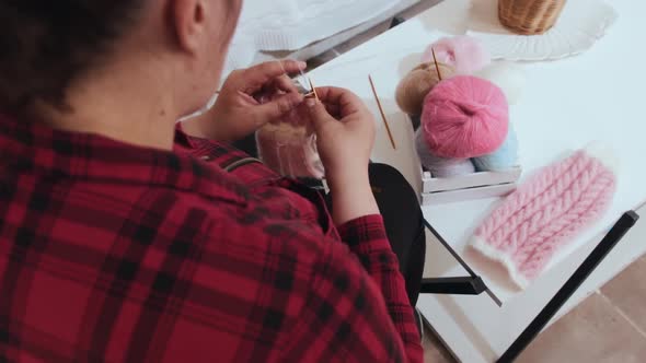 A Woman Knits Puppy Clothes with Knitting Needles