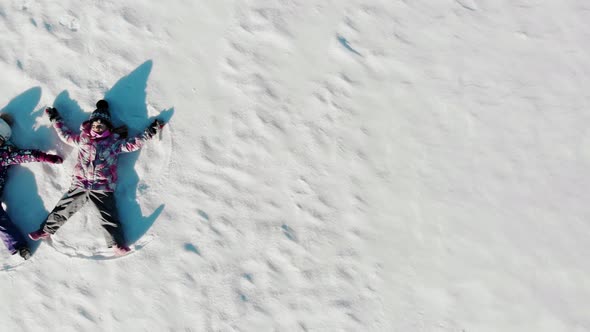 Aerial View From Above of Children Lying on White Snow
