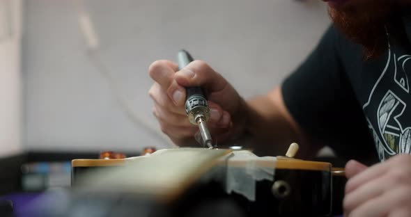 Luthier Heats Frets on Guitar By Soldering Iron Before Refretting Guitar Artisan's Preparations for