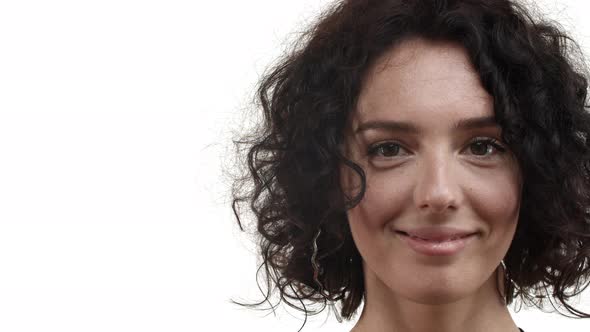 Closeup of Adult Woman with Short Curly Hair Looking at Camera Hopeful Smiling Happy Standing Over