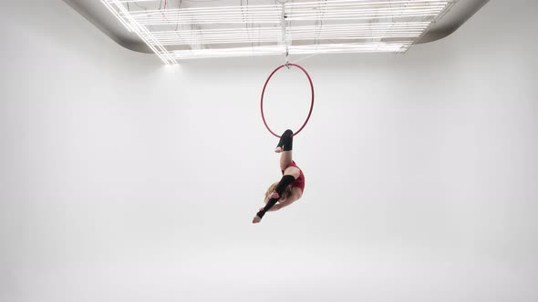 The Girl In The Arch Of The Back Rotates In The Air Ring, In A Red Dress On A White Cyclorama