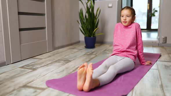 Little Girl Doing Stretching Exercises Practicing Yoga on Fitness Mat at Home