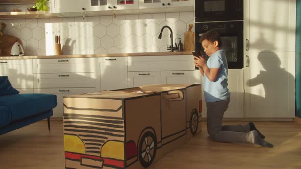 Cute Preadolescent African American Boy Taking Photo of Diy Toy Car on Phone alt