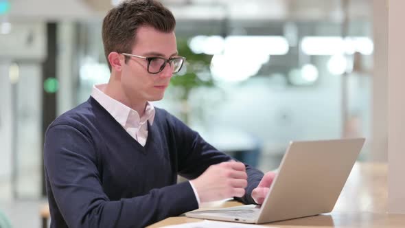 Pensive Young Businessman Thinking and Working on Laptop