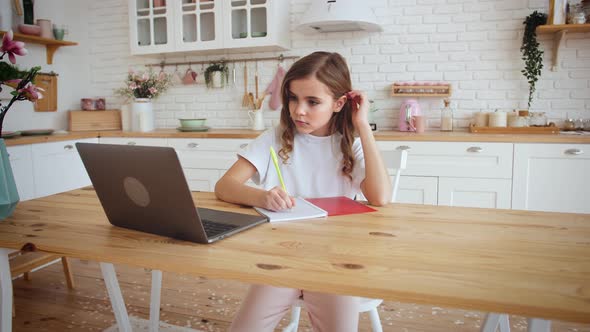 Cute Little Girl Sitting at Kitchen Table Using Laptop for Distance Learning Slow Motion