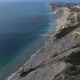 A Paraglider Flies Over a Rock at the Edge of the Sea - VideoHive Item for Sale