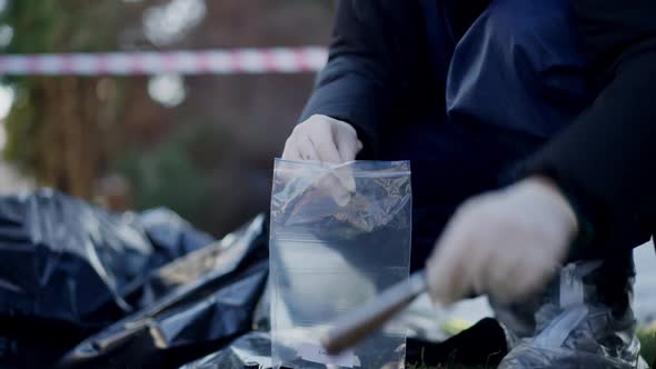 Unrecognizable Criminalist Putting Knife in Transparent Plastic Outdoors