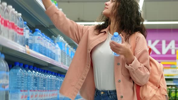 Woman is Buying Bottled Water in Supermarket