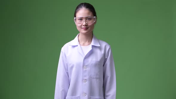 Young Beautiful Asian Woman Doctor Wearing Protective Glasses Smiling with Arms Crossed