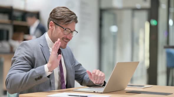 Cheerful Businessman Doing Online Video Chat on Laptop in Office