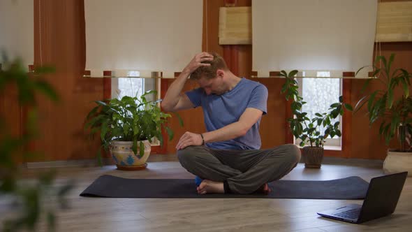 Athletic Young Male Doing Yoga Exercises with Online Instructor Using Internet Connection on Laptop